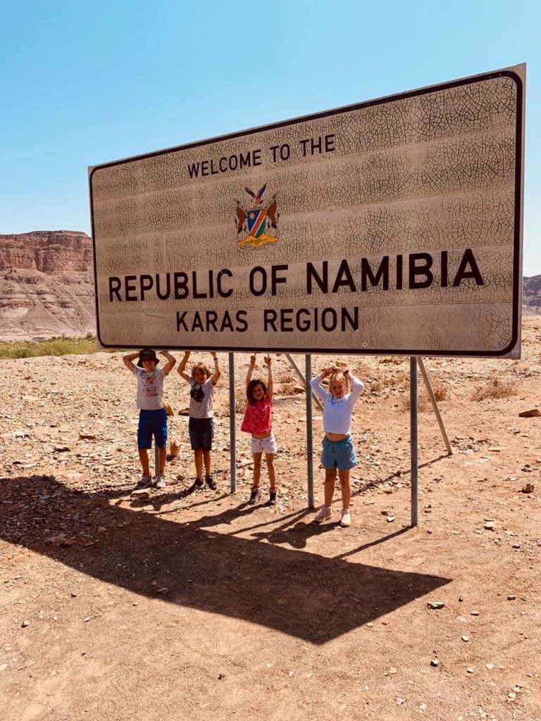 Enfants en dessous du panneau de bienvenue en Namibie